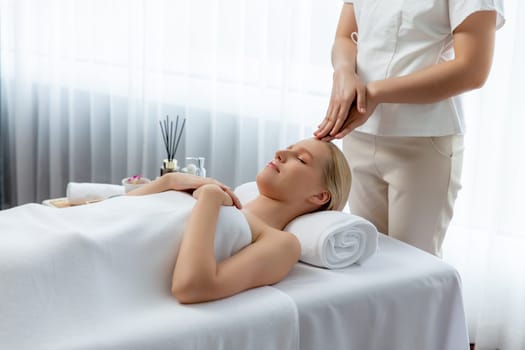 Caucasian woman enjoying relaxing anti-stress head massage and pampering facial beauty skin recreation leisure in dayspa modern light ambient at luxury resort or hotel spa salon. Quiescent