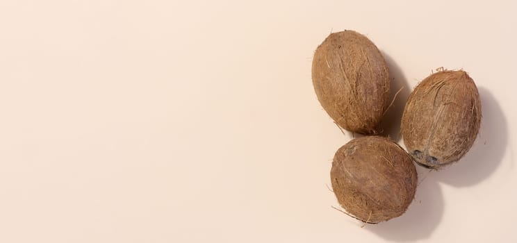 Whole coconut on beige background, top view. Copy space