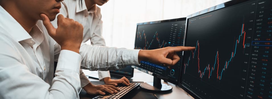 Group of traders discussing on office desk, monitoring stock market on monitor at office workplace. Businessman and broker analyzing stock graph together at stock trading company. Trailblazing