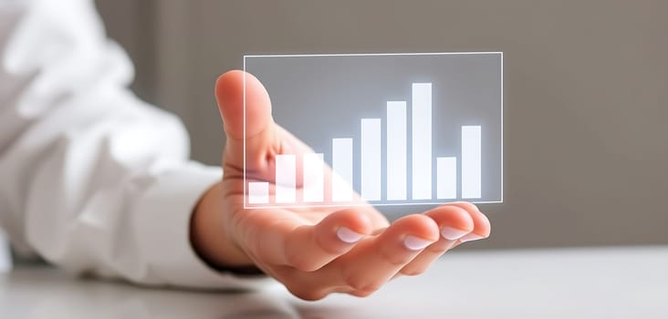 A person presents a clear bar graph hologram, symbolizing financial growth and data analysis in a modern office setting, with natural light illuminating the workspace.