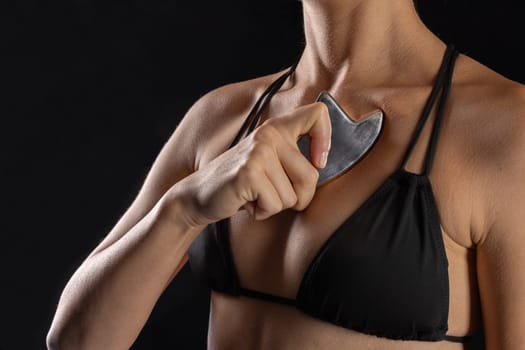 woman uses metal tool for massage and soft tissue mobilization, Intelligent stainless steel IASTM instruments for soft tissue massage and pain relief, black background