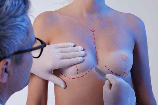doctor holding scalpel near woman breast before surgery, creative concept to increase breast shape and size