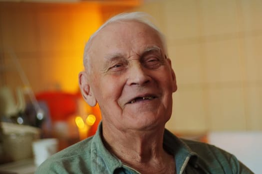 An elderly man sits contentedly in a kitchen, basking in the soft light of the late afternoon. His peaceful expression reflects a sense of warmth and happiness