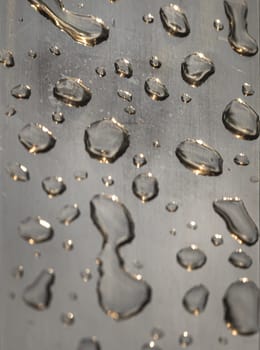 Close up of Rain water drops on the metallic surface. Water droplets caused by rain perched on a stainless steel handle, Natural Pattern of raindrops or dew drops on silver metal background for wallpaper poster and banner design, Selective focus.