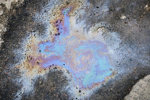 Leakage of oil or gasoline from a car onto a wet asphalt road.