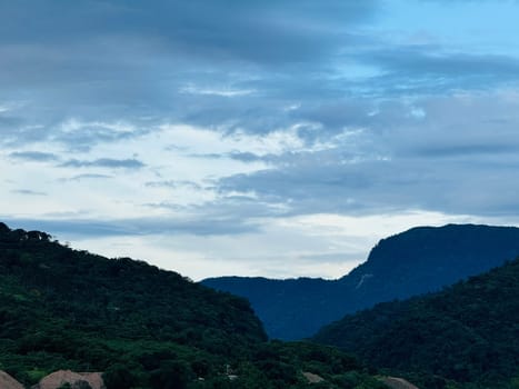 The landscape showcases majestic mountains and valleys under a dramatic sky filled with clouds, creating a serene atmosphere at dusk.