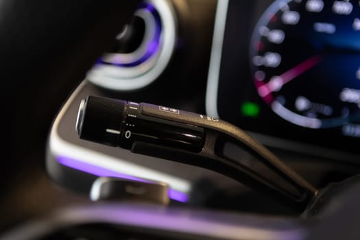 Close-up view of a car indicator control lever with a blurred dashboard in the background, showcasing modern automotive design and interior details with soft ambient lighting.