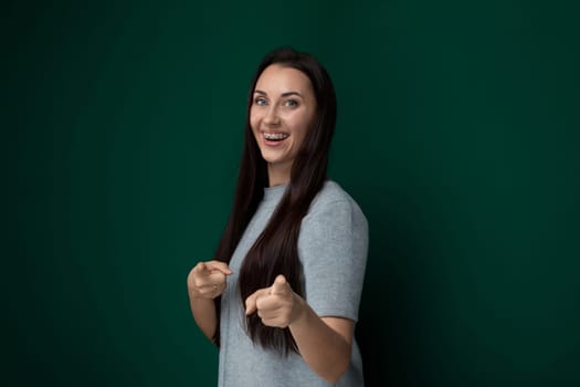 A woman with long hair is shown pointing to the side with her arm extended. She appears to be indicating or drawing attention to something off-camera.