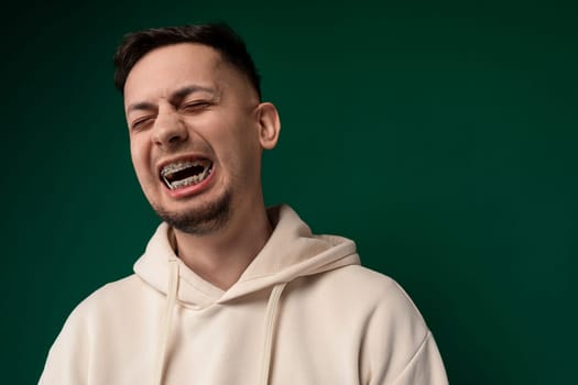 A man wearing a white hoodie with his mouth open, possibly speaking or expressing surprise. His facial expression suggests emotion and engagement.