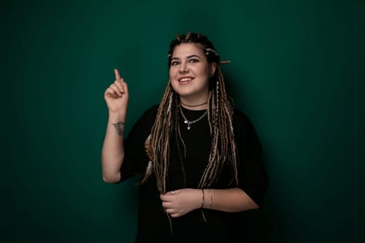A woman with long dreadlocks pointing at an object outside of the frame. She appears focused and engaged, directing attention towards a specific point. Her gesture suggests curiosity or emphasis.