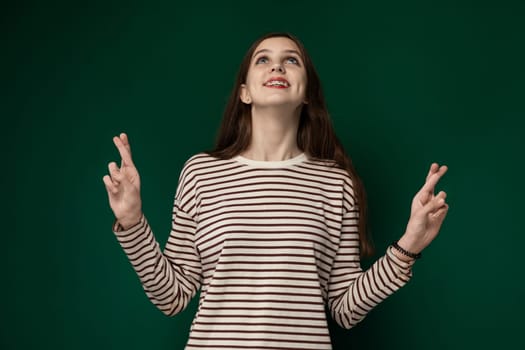 A woman is standing in front of a vibrant green wall. She appears contemplative while looking in the distance. The contrast between her figure and the wall creates a striking visual impact.