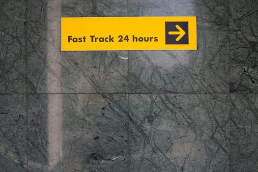 Sign on wall that says Fast Track 24 Hours and arrow for way. Sign to help guide you in an unfamiliar place for travelers on wall