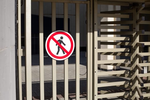 Metal gate with no walking sign on it. Special checkpoint with rotating passage for security when entering the protected area. Passage of people is prohibited