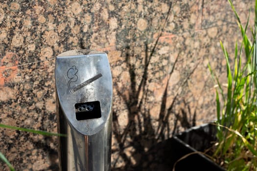 Street metal pole ashtray in smoking area near the building, social problem of cigarette smoking addiction, hole for extinguishing cigarettes on street in response to bad habit