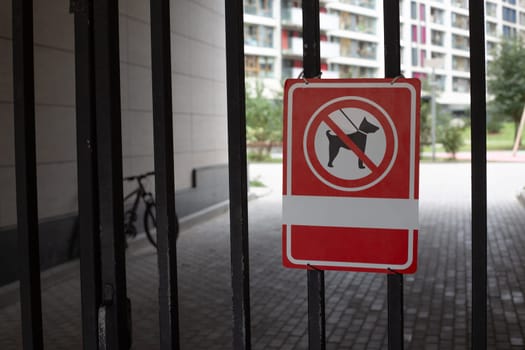 Sign on metal fence at entrance to yard prohibits walking dogs. Prohibition on passage of dogs in protected area on city street