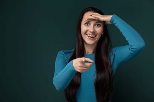 A woman with long black hair is shown in the image, holding her hands up to her face. Her facial expression is not discernible, but her hands seem to be delicately placed near her cheeks in a thoughtful pose.