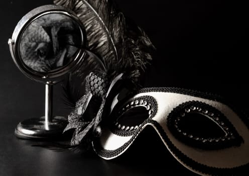 Bangkok, Thailand - 17 Sep, 2024 - Beautiful mysterious venetian mask with Feathers design and Silver round mirror on black background, Light and Shadow, Copy space. Selective Focus.