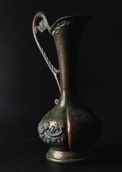 Bangkok, Thailand - 17 Sep, 2024 - Antique carved iron jug or vase on Black background.  Light and Shadow, Space for text, Selective focus.