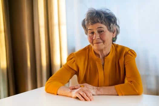 A portrait of a laughing, smiling elderly woman with gray hair and wrinkles on her face, but young at heart and leading an active lifestyle. Happy pensioner is pretty posing in her cozy home.