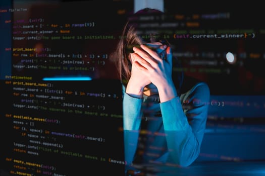 Young girl hides her face with hands, works on a laptop late at night online, a tired woman is coding and overworked, using her device to create a new project and e-learning, getting an IT education.