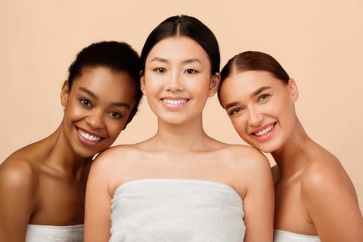 Female Beauty Concept. Three Mixed Girls Wrapped In Towels Smiling To Camera Posing In Studio On White Background.