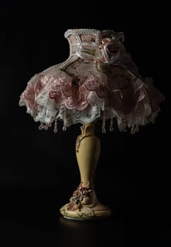 Bangkok, Thailand - 19 Sep, 2024 - Lace fabric desk Lamp shade table with Rococo baroque style on black background. Light and Shadow, Dark tone, Space for text, Selective focus.