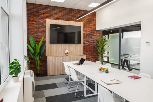 This room features a desk, chairs, and a flat screen TV. The desk is in the center, with chairs placed around it. A sleek flat screen TV is mounted on the wall, completing the modern setup.