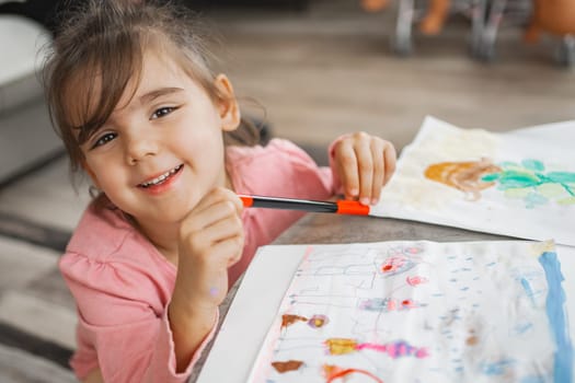 A happy young girl creates vibrant artwork with colored pens.
