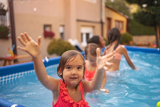 A young girl joyfully splashes water while playing with friends outdoors.