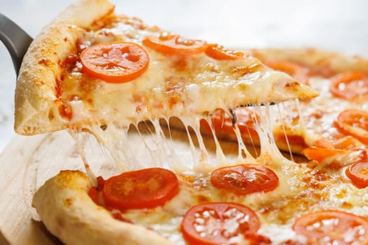 cut off a slice of pizza. melted cheese stretches from the piece