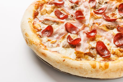 Close-up of a freshly baked pizza with pepperoni, ham, and mushrooms on a white background.