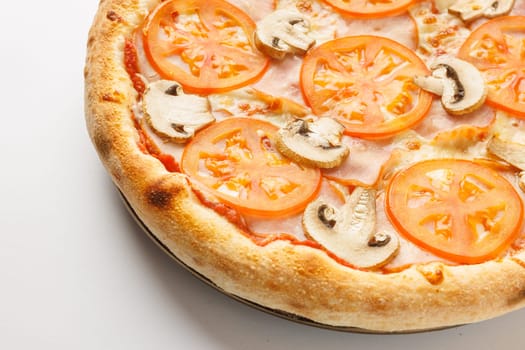 A close-up of a freshly baked pizza topped with tomato slices and mushrooms on a white background.