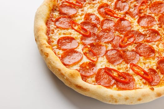 Close-up of a pepperoni pizza with red chili slices on a white background.