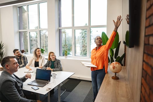 A diverse group of individuals sitting around a table with laptops, engaged in discussions and working collaboratively on projects. The scene showcases teamwork, technology, and modern workplace dynamics.