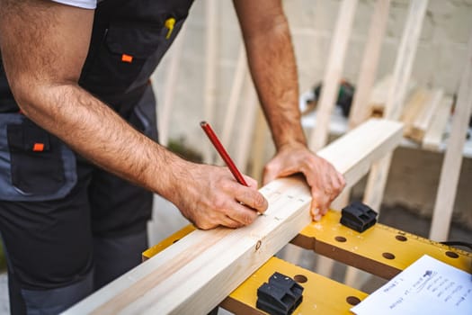 Unrecognizable men measuring wooden plank outdoors.