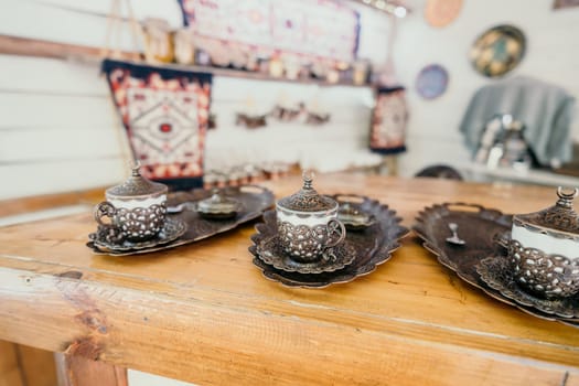 Three traditional Turkish coffee cups with ornate metalwork sit on a wooden table, ready for a delicious brew.