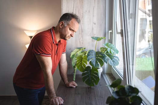 Man standing by the window looking sad and distraught.