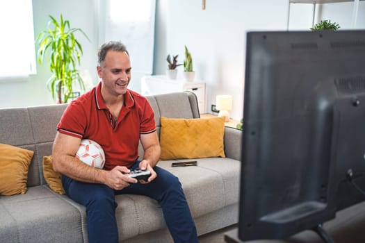 Middle age Caucasian man playing soccer video game at home.