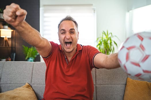 Excited middle aged man watching soccer game at home.
