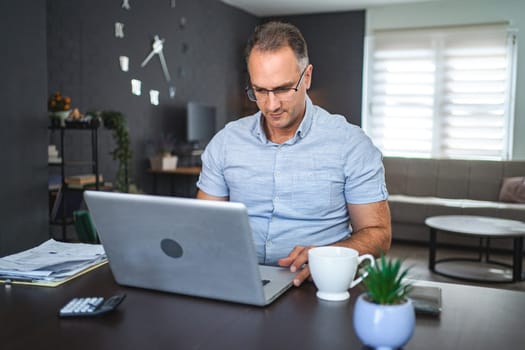 Middle aged Caucasian man working on laptop at home.