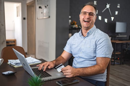 Middle aged Caucasian man online shopping on laptop at home.