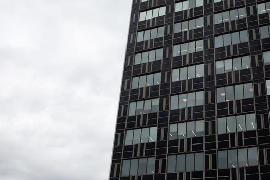Ordinary boring office building against gray sky. Sad office work in gloomy atmosphere. Exterior of office building in cloudy routine day