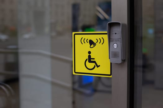 Button to call staff to assist person with disabilities at entrance. Accessible environment for people in wheelchair, entrance to modern building with conditions for the disabled people