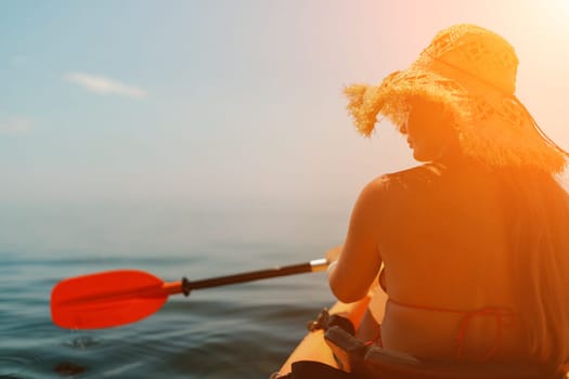 Woman in kayak back view. Happy woman with long hair in a swimsuit and hat floating in kayak on the sea. Summer holiday vacation. Summer holidays vacation at sea