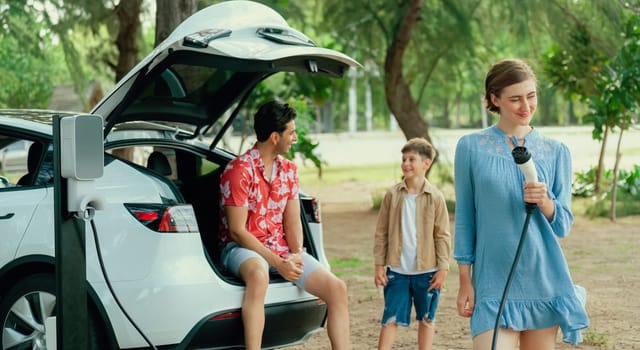 Family road trip vacation with electric vehicle, lovely family recharge EV car with green and clean energy. Natural and eco friendly car travel for sustainable environment. Perpetual