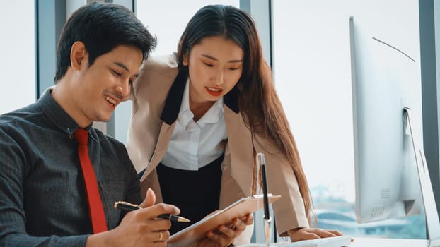 Two business people talk project strategy at office meeting room. Businessman discuss project planning with colleague at modern workplace while having conversation and advice on financial report. Jivy