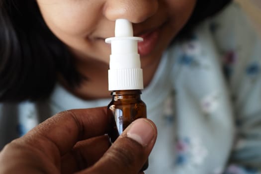 close up of sick child using nasal medicine spray.