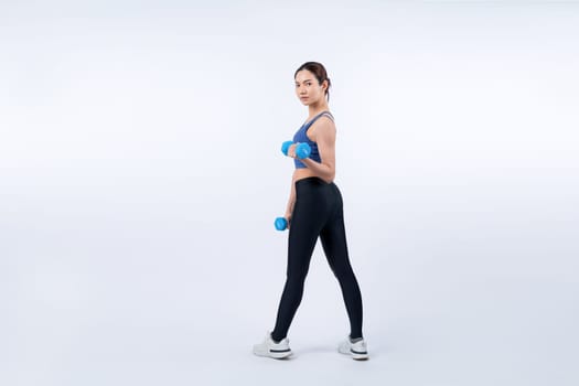 Vigorous energetic woman doing dumbbell weight lifting exercise on isolated background. Young athletic asian woman strength and endurance training session as body workout routine.