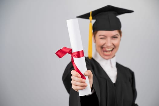 Emotional woman in graduate gown holding diploma in foreground
