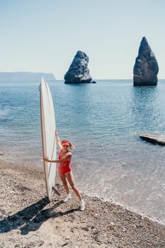 Close up shot of beautiful young caucasian woman with black hair and freckles looking at camera and smiling. Cute woman portrait in a pink bikini posing on a volcanic rock high above the sea